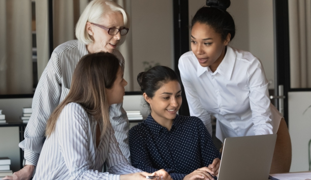 Multigenerational female employees working in a conference room together.