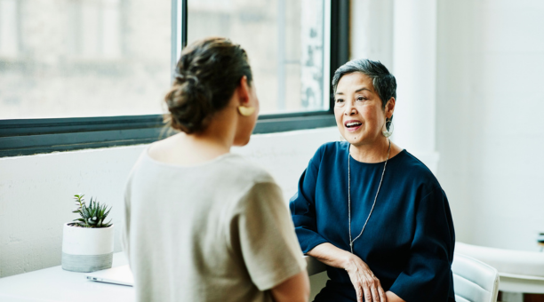 Benefits administrator meeting with an employee as they face each other.
