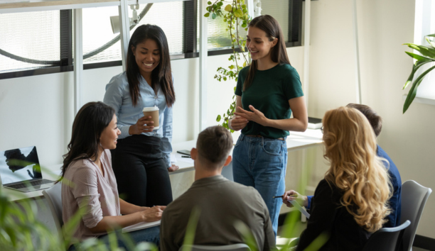 Young adult employees talking and laughing in a conference room.