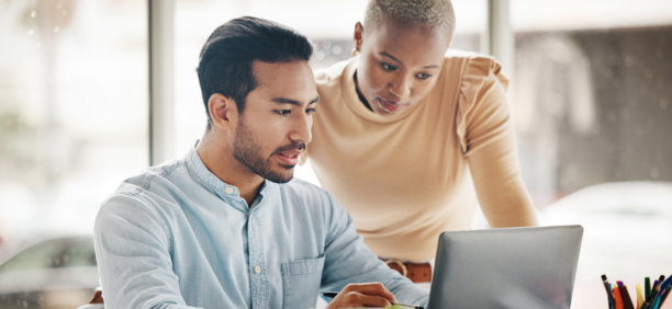 Two employees looking at a laptop together at work.