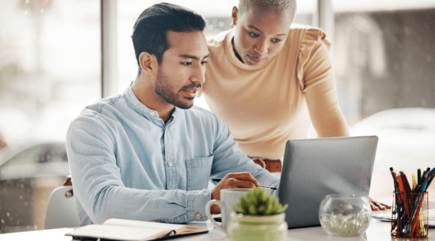 Two employees looking at a laptop together at work.