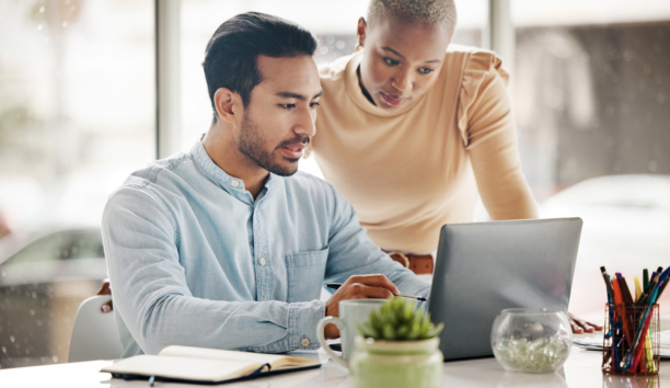 Two employees looking at a laptop together at work.
